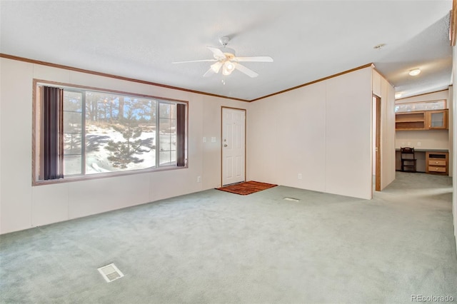 unfurnished living room featuring crown molding, built in desk, light colored carpet, and ceiling fan