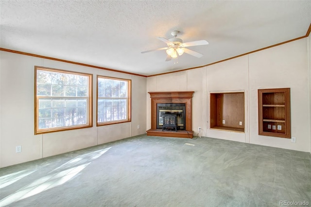 unfurnished living room with ceiling fan, ornamental molding, a textured ceiling, and carpet