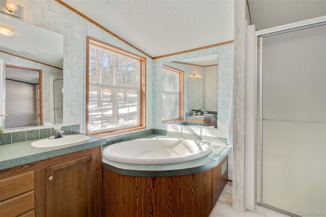 bathroom with vaulted ceiling, independent shower and bath, ornamental molding, vanity, and a textured ceiling