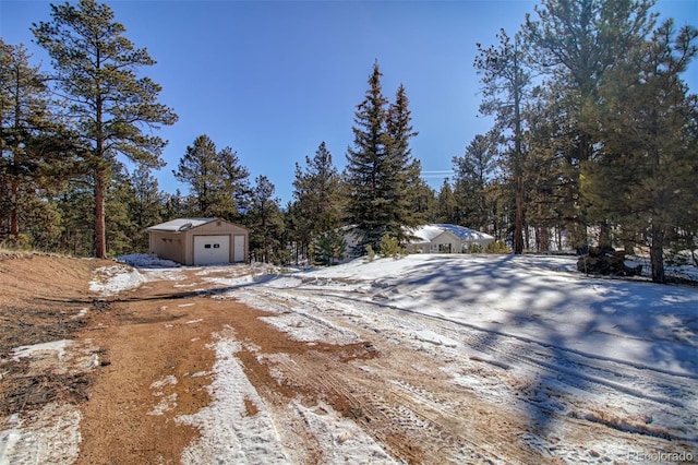 yard layered in snow featuring a garage and an outdoor structure