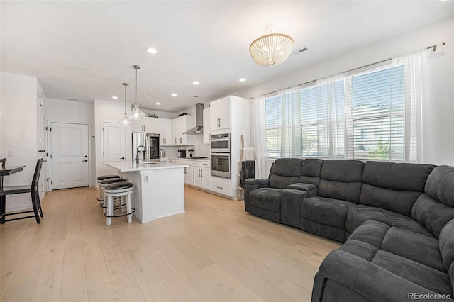 living room with recessed lighting, light wood-style flooring, and visible vents