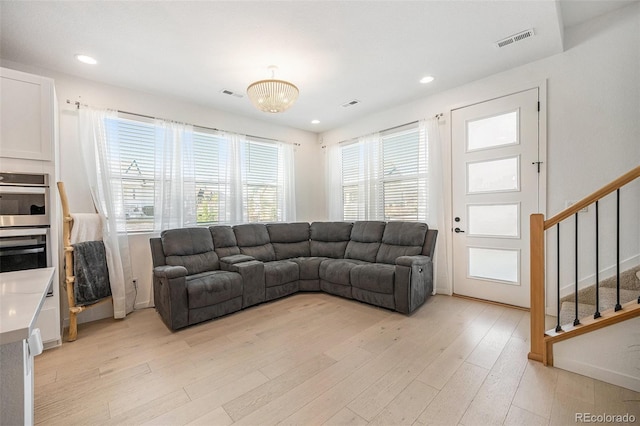living room featuring visible vents, light wood finished floors, and a wealth of natural light