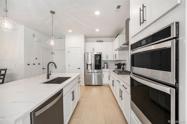 kitchen with appliances with stainless steel finishes, light stone countertops, a sink, recessed lighting, and white cabinetry