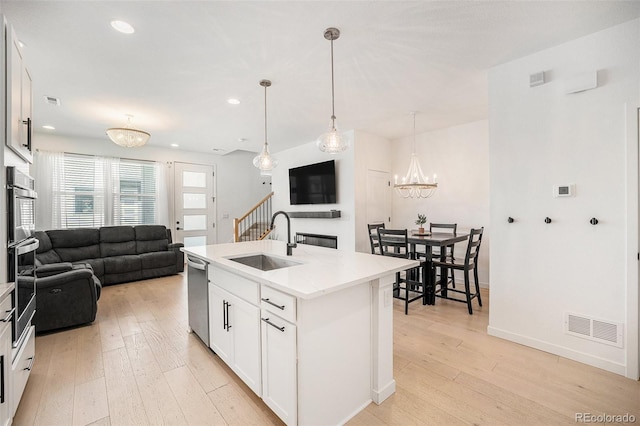 kitchen featuring visible vents, appliances with stainless steel finishes, light wood-type flooring, a sink, and open floor plan