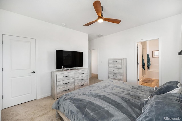 bedroom featuring a ceiling fan, light colored carpet, visible vents, baseboards, and ensuite bathroom
