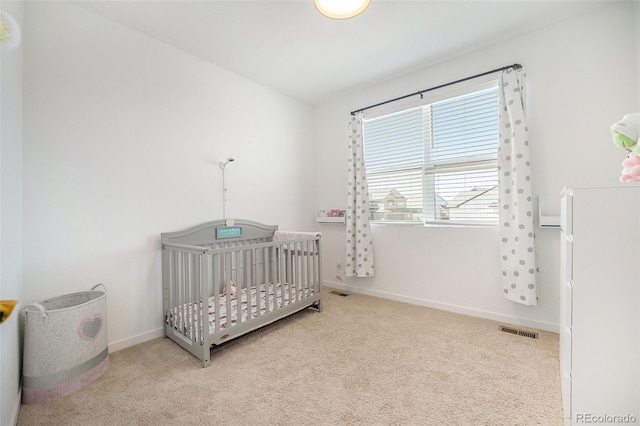 carpeted bedroom with visible vents, baseboards, and a nursery area