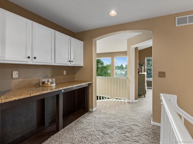 10216 Kleinbrook Way, Highlands Ranch, CO 80126 - kitchen featuring arched walkways, light carpet, white cabinetry, light stone counters, and recessed lighting