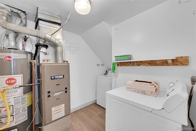 clothes washing area with separate washer and dryer, water heater, and light wood-type flooring