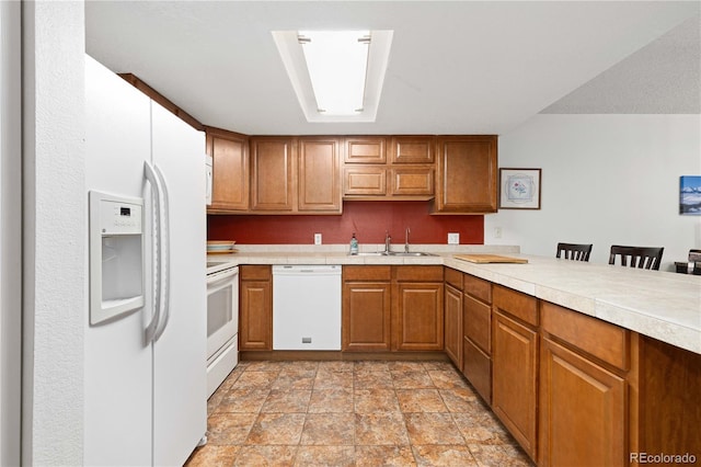 kitchen with sink, white appliances, kitchen peninsula, and a breakfast bar area