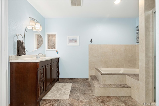 bathroom with vanity and a relaxing tiled tub