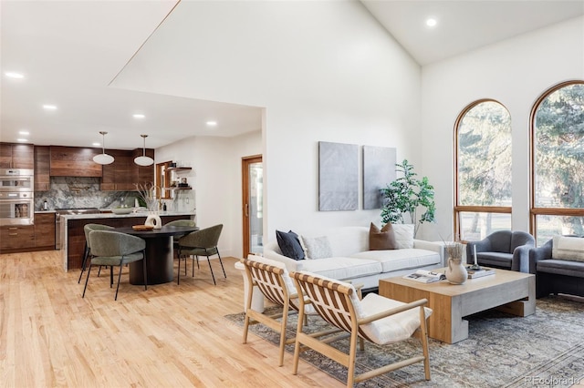 living room with high vaulted ceiling, light wood-style floors, and recessed lighting