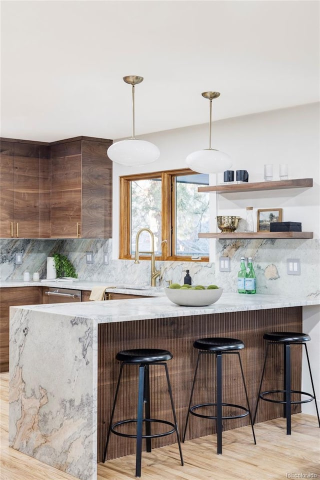 bar featuring dishwasher, a sink, light wood-type flooring, pendant lighting, and decorative backsplash