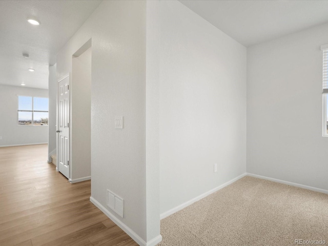 corridor featuring baseboards, recessed lighting, and light wood-type flooring