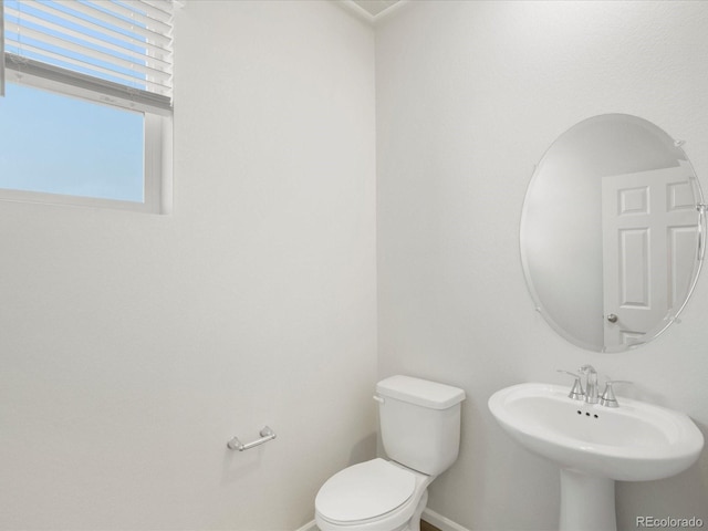 bathroom with baseboards, toilet, and a sink