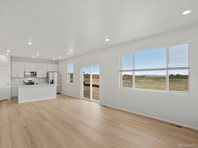 unfurnished living room featuring light wood-style floors, baseboards, and recessed lighting
