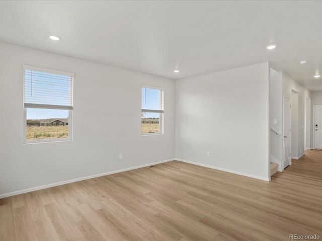 empty room with light wood finished floors, recessed lighting, baseboards, and stairs