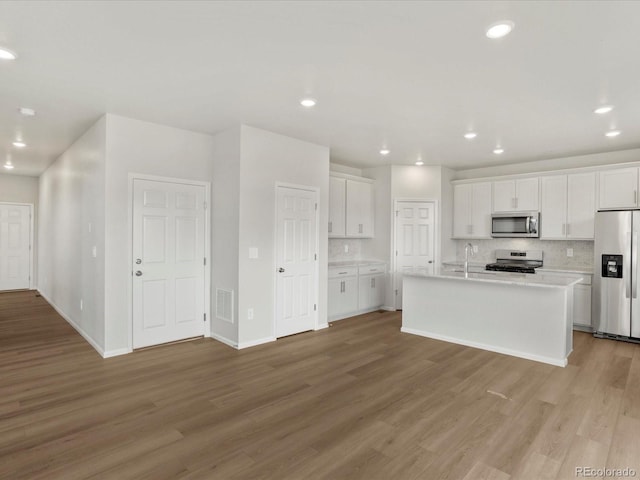 kitchen with stainless steel appliances, light wood finished floors, light countertops, white cabinets, and a sink