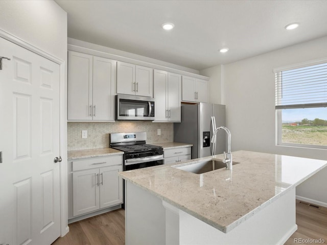 kitchen with stainless steel appliances, light wood finished floors, a sink, backsplash, and recessed lighting