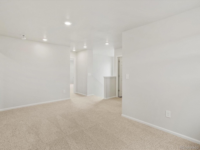 empty room featuring light colored carpet, recessed lighting, and baseboards