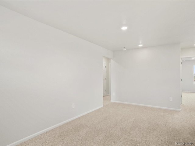 empty room featuring light colored carpet, recessed lighting, and baseboards