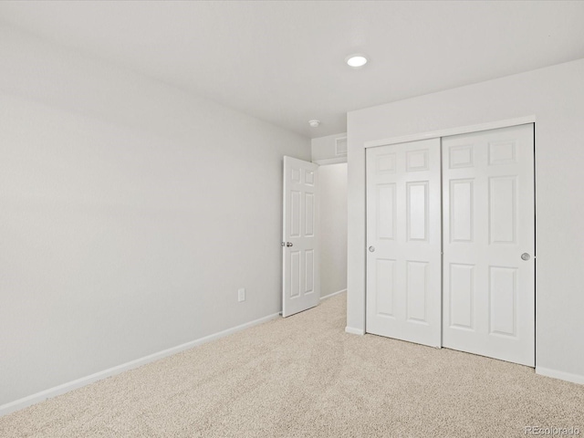 unfurnished bedroom featuring light colored carpet, baseboards, and a closet