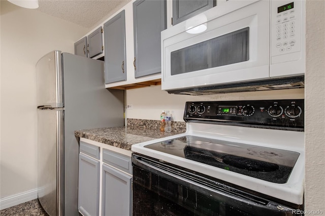 kitchen with stainless steel fridge, a textured ceiling, gray cabinets, and range