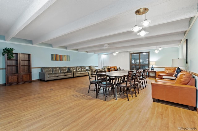 dining area with an inviting chandelier, a textured ceiling, light hardwood / wood-style floors, and beamed ceiling