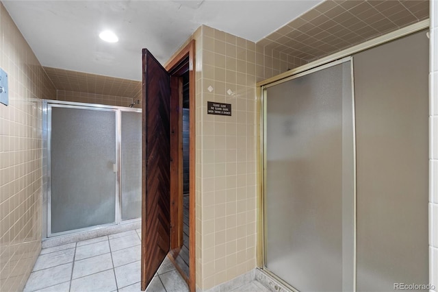 bathroom featuring walk in shower, tile walls, and tile floors