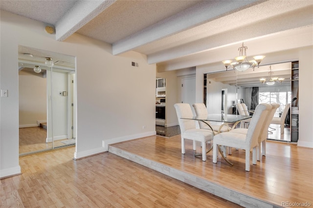 dining room featuring a notable chandelier, a textured ceiling, light hardwood / wood-style floors, and beam ceiling