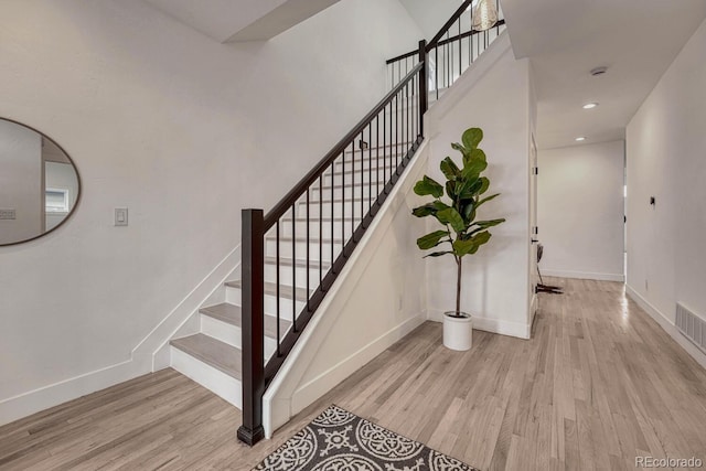 stairway featuring wood finished floors, baseboards, and recessed lighting