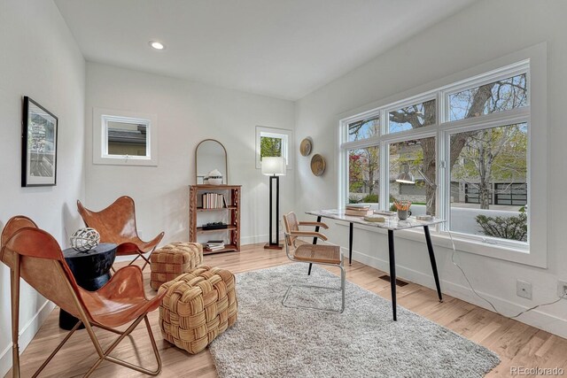 living area with baseboards, light wood-type flooring, and recessed lighting