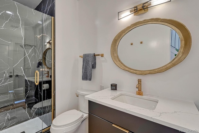 full bathroom featuring a marble finish shower, toilet, and vanity