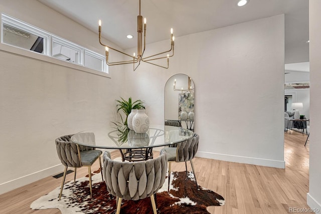 dining area with a chandelier, wood finished floors, baseboards, recessed lighting, and arched walkways