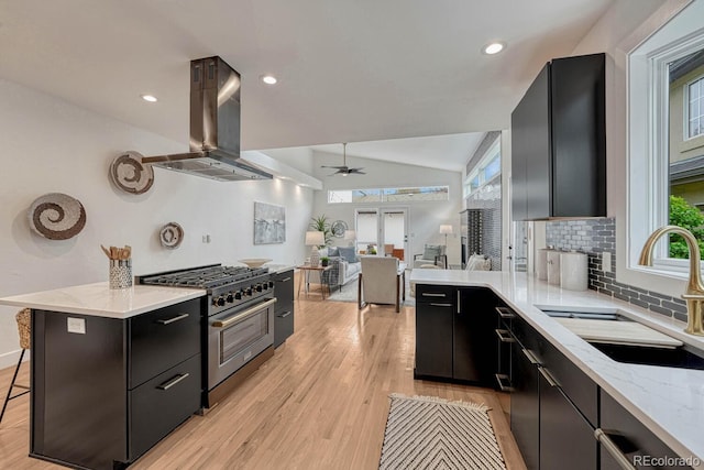 kitchen with high end range, a sink, island exhaust hood, dark cabinets, and a ceiling fan