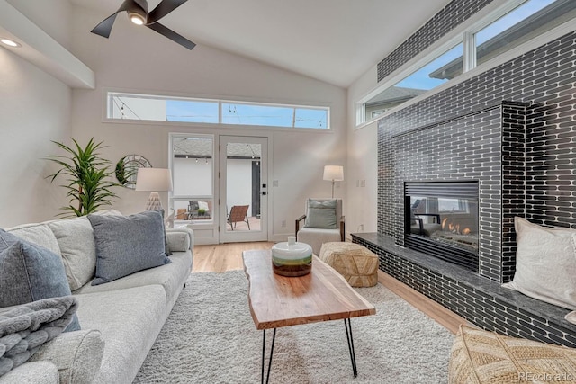 living room with lofted ceiling, wood finished floors, a fireplace, and ceiling fan