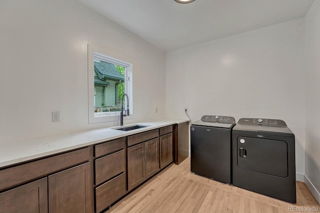 laundry area featuring a sink, washer and clothes dryer, and light wood finished floors