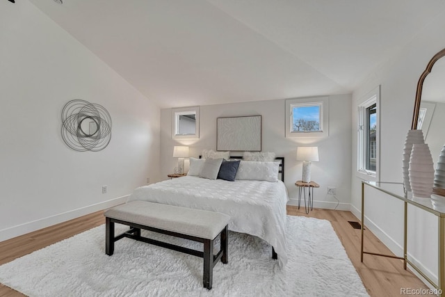 bedroom with light wood-style flooring, baseboards, and vaulted ceiling