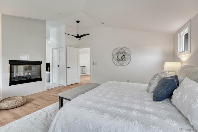 bedroom featuring wood finished floors, lofted ceiling, a tile fireplace, and radiator heating unit