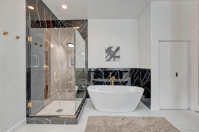 bathroom with a soaking tub, a shower stall, tile walls, recessed lighting, and tile patterned flooring