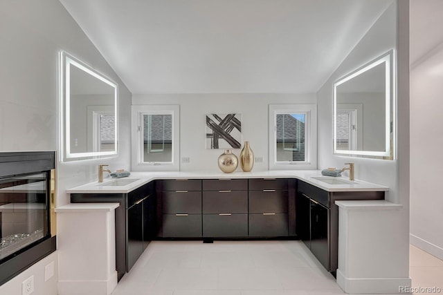kitchen with vaulted ceiling, a sink, light countertops, beverage cooler, and modern cabinets