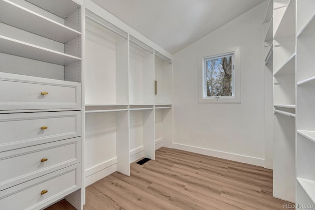 walk in closet with vaulted ceiling and light wood-style flooring