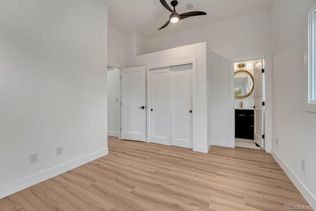 unfurnished bedroom featuring light wood finished floors, baseboards, ensuite bathroom, and a closet