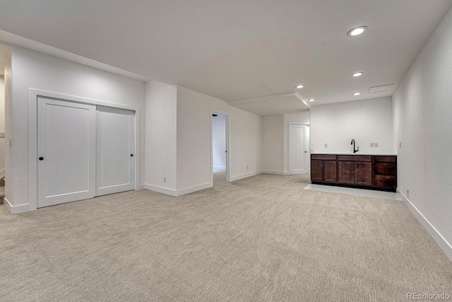 unfurnished living room with light carpet, recessed lighting, baseboards, and bar area