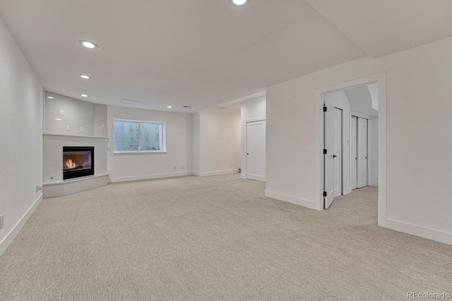 unfurnished living room featuring light carpet, recessed lighting, baseboards, and a large fireplace