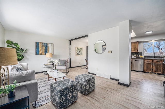 living room with visible vents, baseboards, and light wood-style floors