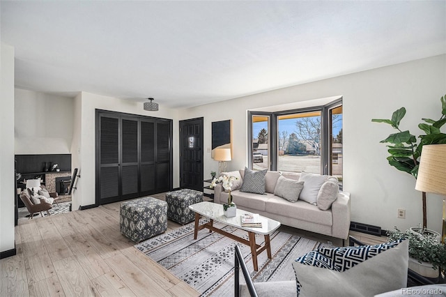 living area featuring a fireplace, baseboards, and hardwood / wood-style floors