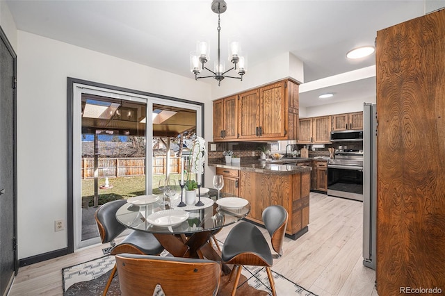 dining space featuring light wood-type flooring, baseboards, and an inviting chandelier