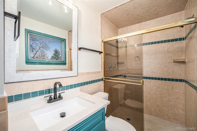 bathroom with vanity, tile walls, toilet, and a stall shower