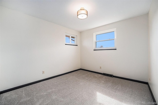 carpeted empty room with visible vents and baseboards