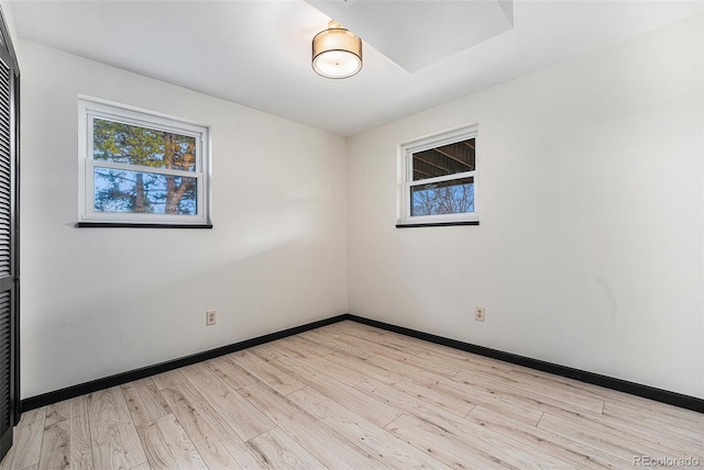 unfurnished room with a healthy amount of sunlight, baseboards, and light wood finished floors